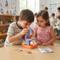 Boy in striped tee peering through microscope eyepiece with concentration while girl in pink floral dress watches beside him with specimen slides and My First Science Lab booklet on table