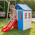 Girl smiling from top of playhouse slide toddler boy mid-slide laughing with joy child waving from arched window golden hour garden with wooden swing set and green hedge