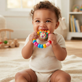 Happy baby holding and chewing colourful lion teether rattle ring toy