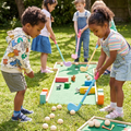 Four children playing mini golf on a wooden course on a sunny garden lawn with colourful block obstacles and tiny animal figurines